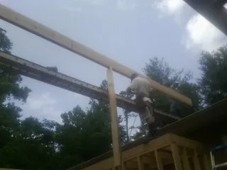 Carpenter setting a ridge beam over a new addition frame — Ice Dam Removal by Roofing Brothers in Wild Rose