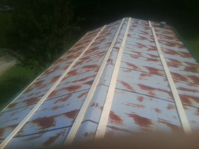 Rusted metal roof panels with new wood purlins before replacement — Storm Damage Roof Repair in Wild Rose by Roofing Brothers