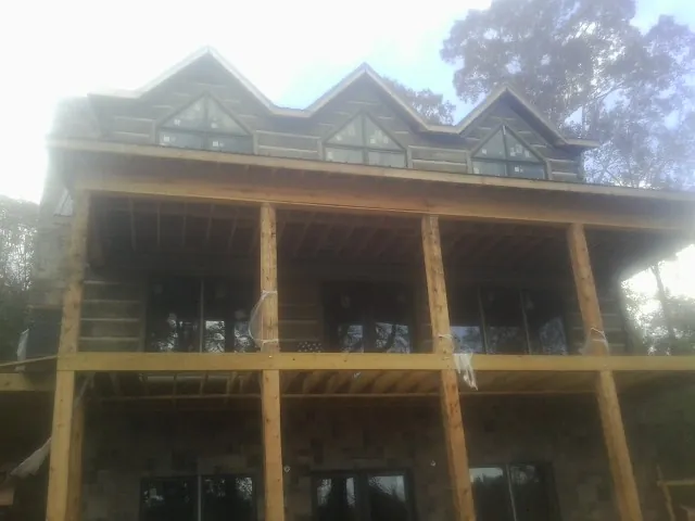 Dormers and porch framing on a large log home under construction — Roof Coating work by our crew in Wild Rose