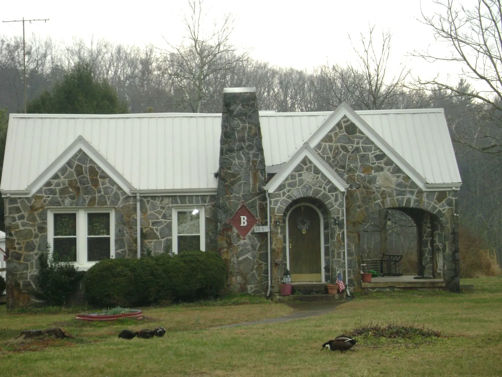 White metal roof on a stone cottage with steep gables in Wild Rose