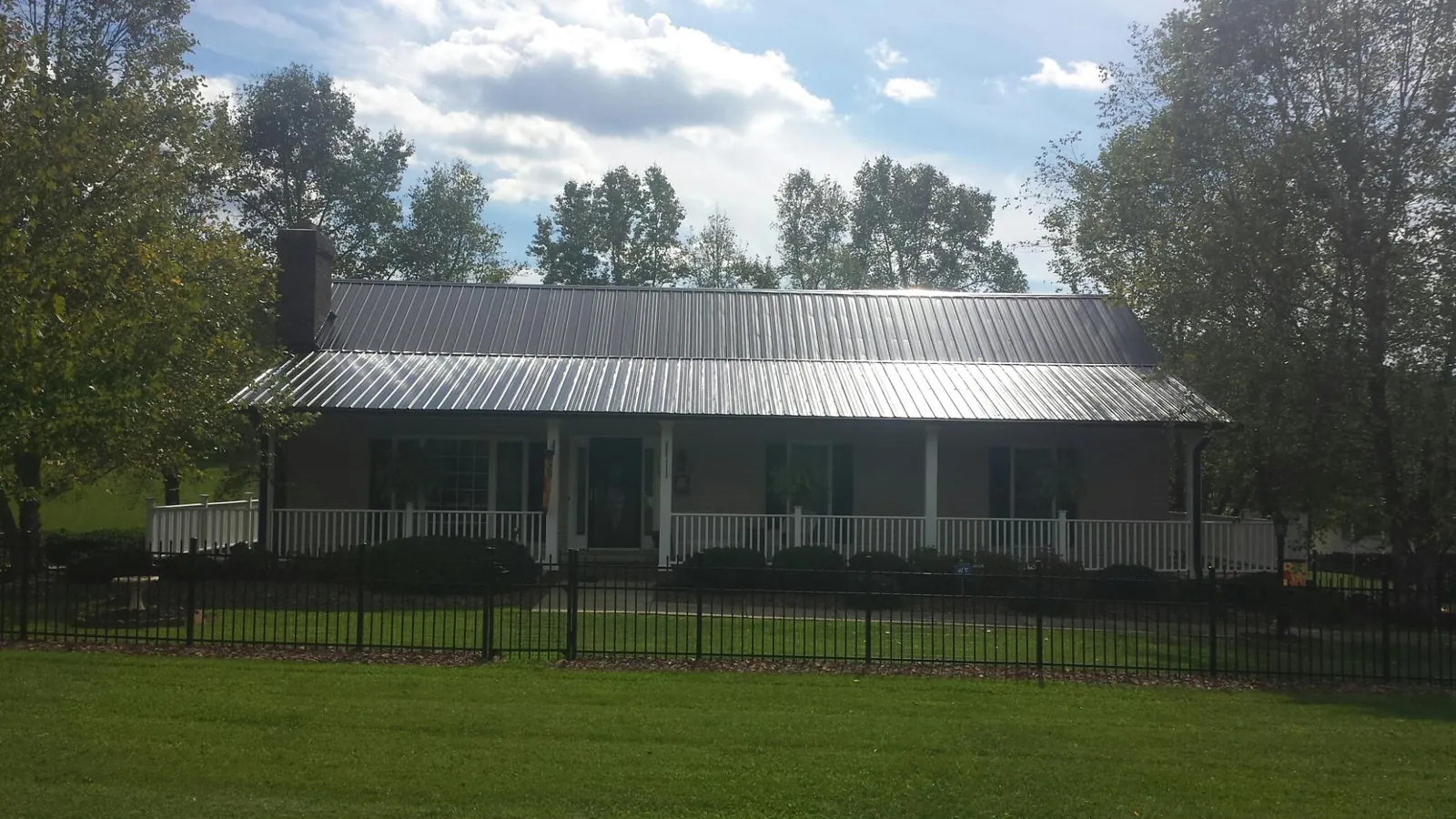 Gray metal roof on a brick ranch with a full width front porch — Gutter Guard Installation work by our crew in Wild Rose
