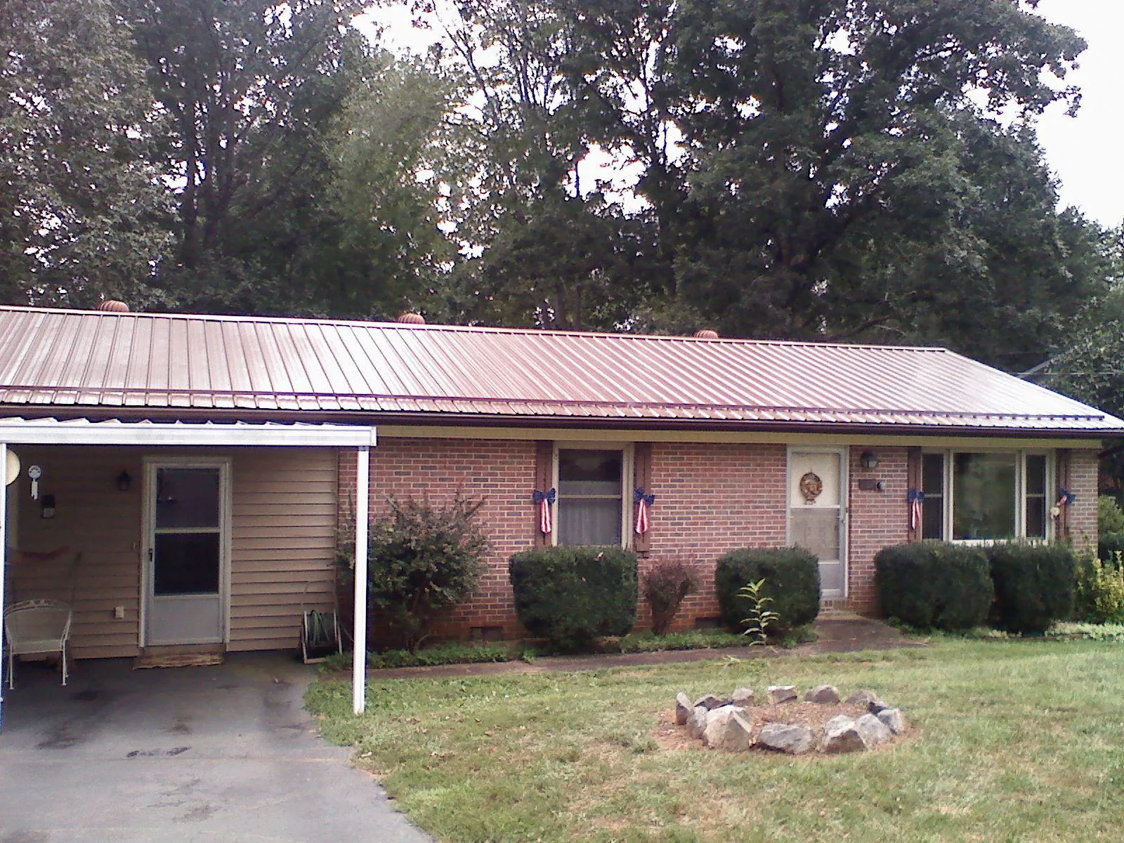 Bronze metal roof and carport on a brick ranch home — Roof Repair work by our crew in Wild Rose