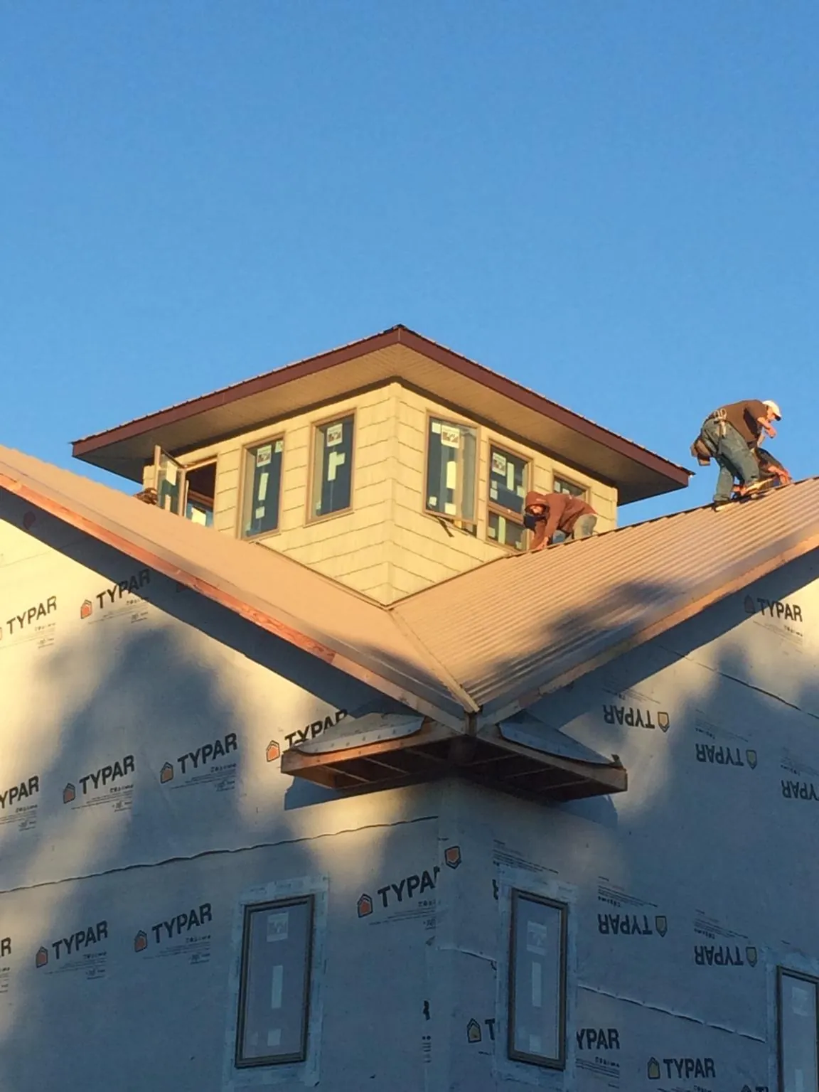 Roofers working around a rooftop cupola on a new metal roof at sunset — Roof Waterproofing in Wild Rose by Roofing Brothers